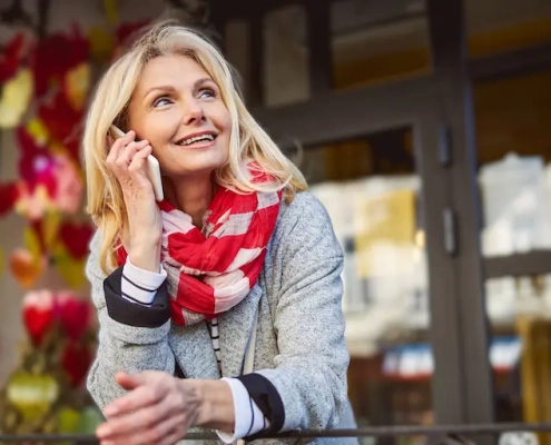 Femme de 60 ans blonde et souriante au téléphone