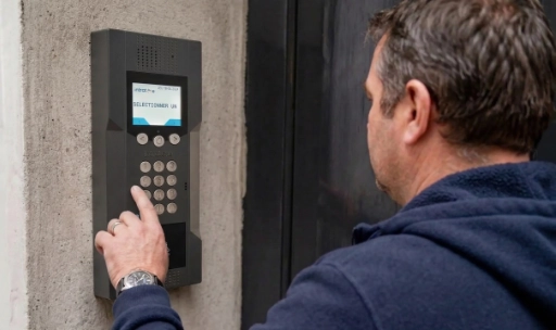 installation interphone intratone dans copropriété à marseille Homme appuyant sur un interphone mural moderne.